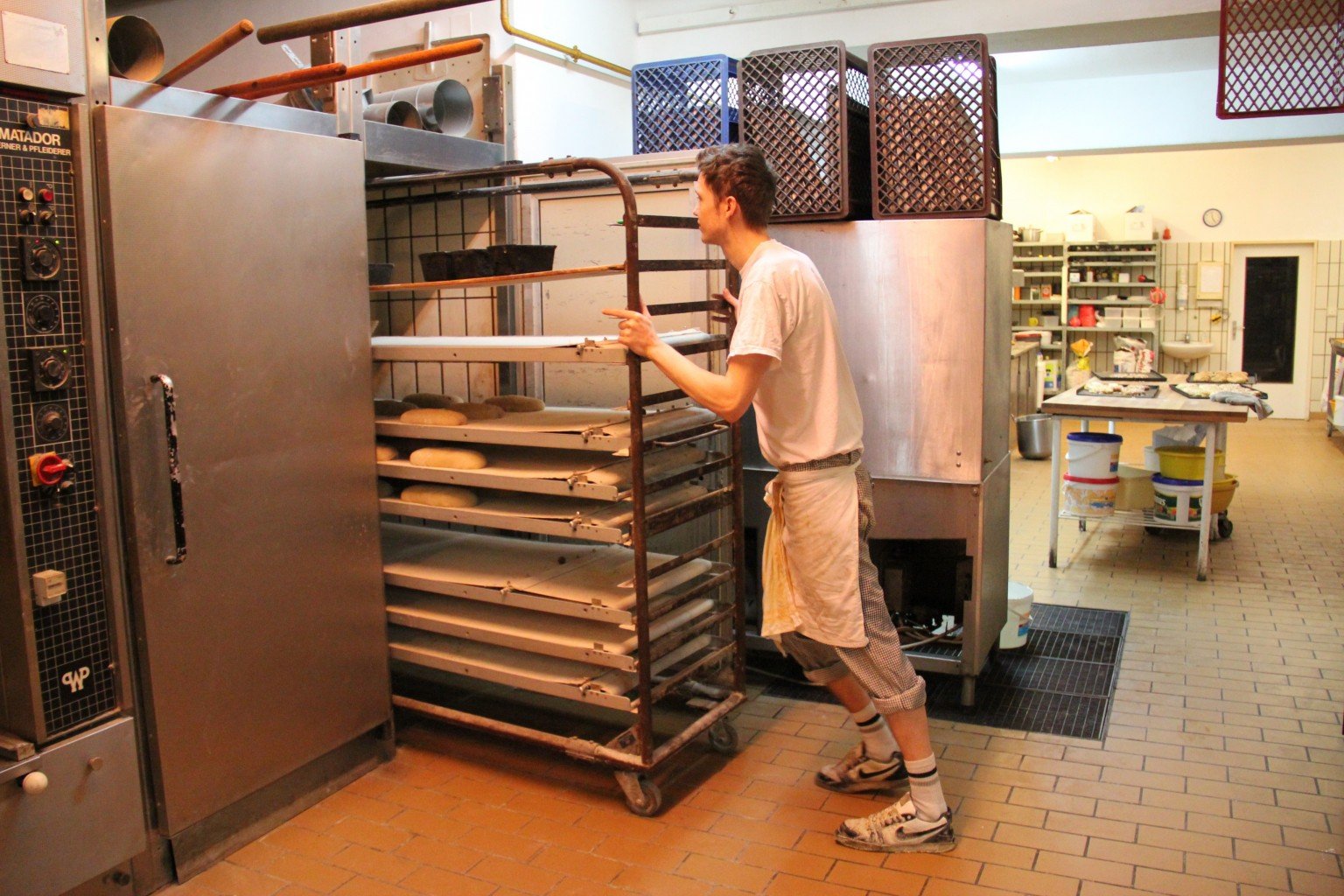 Geselle schiebt Brot in den Ofen